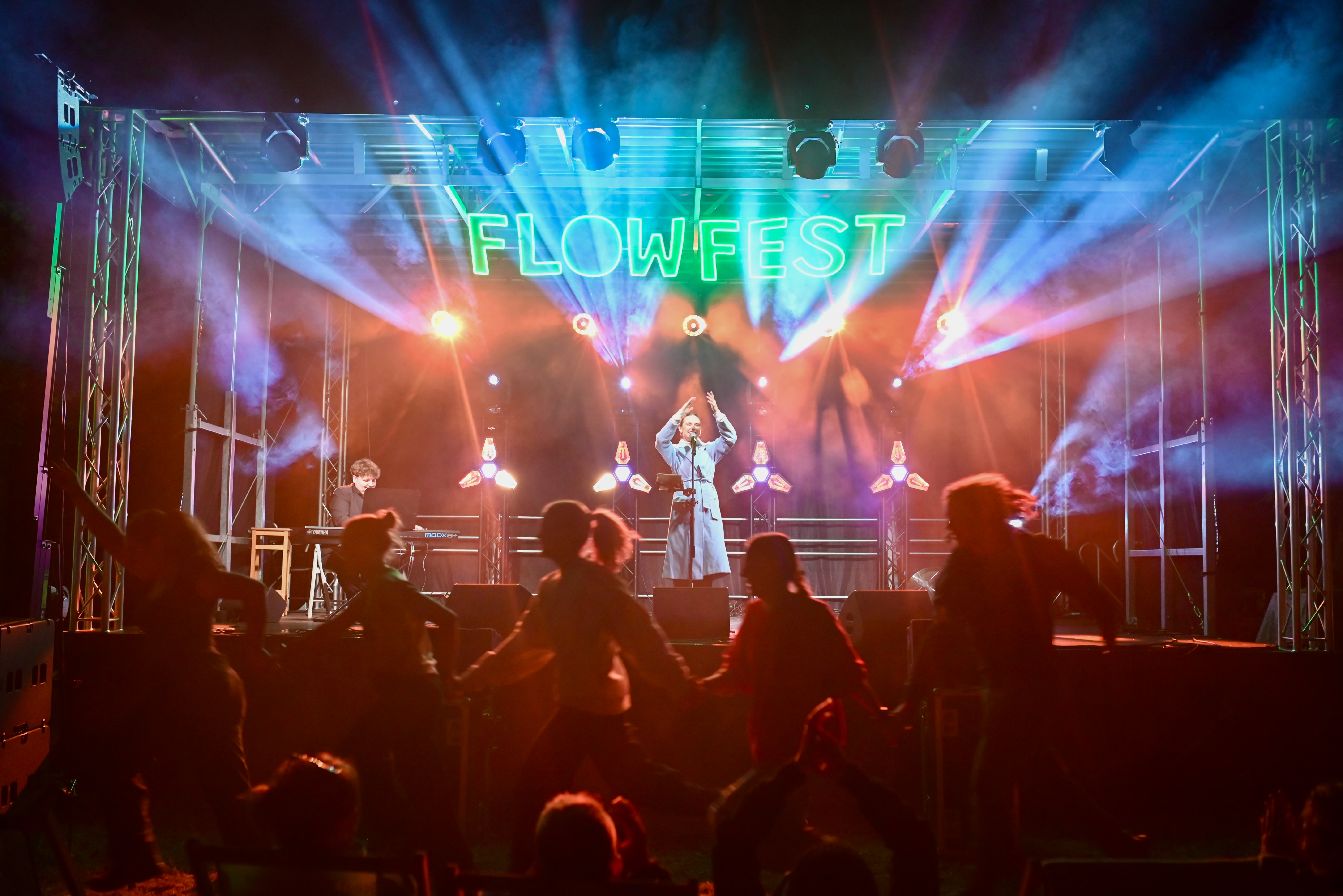 Scena FlowFest nocą — publiczność tańczy pod neonem